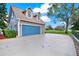 Home's exterior showcasing a blue two car garage door, dormer windows and luscious yard at 17416 Magnolia Island Blvd, Clermont, FL 34711