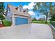 Garage with a blue door and ample parking space with manicured landscape at 17416 Magnolia Island Blvd, Clermont, FL 34711