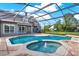 Screened-in pool area featuring a kidney shaped pool and integrated spa, all surrounded by brick pavers at 17416 Magnolia Island Blvd, Clermont, FL 34711