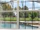 View of backyard pool and spa through wall of windows and outdoor foliage at 17416 Magnolia Island Blvd, Clermont, FL 34711