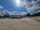 View of the home with white exterior, metal roof, front driveway and partial blue sky at 1912 Providence Rd, Lakeland, FL 33805