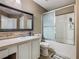 Well-lit bathroom featuring tiled floors, a vanity with a mirror, toilet, and a tub with sliding doors at 2448 Brownwood Dr, Mulberry, FL 33860