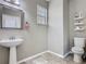 Cozy bathroom with pedestal sink, framed mirror, toilet, and open shelving for storage at 2448 Brownwood Dr, Mulberry, FL 33860