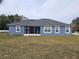 Rear exterior view of home with a screened in porch with a green lawn at 1264 Buckeye Ne Rd, Winter Haven, FL 33881