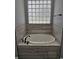 Relaxing bathtub with tiled surround, decorative tiled accents and natural light at 1264 Buckeye Ne Rd, Winter Haven, FL 33881