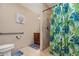 Bathroom featuring a walk-in shower with green curtains, grab bar, and neutral tiles providing accessibility at 1176 Balfour Dr, Deltona, FL 32725