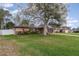 Spacious one-story home with a large front lawn, mature tree, and attached two-car garage on a sunny day at 1176 Balfour Dr, Deltona, FL 32725