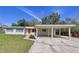 Inviting home featuring a bright orange door, carport, and well-maintained lawn at 1625 Avenue D Ne, Winter Haven, FL 33881