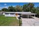 Charming single-story home with carport, tidy lawn, and a vibrant orange front door, nestled among lush trees at 1625 Avenue D Ne, Winter Haven, FL 33881