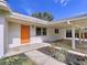 Charming single-story home with an orange front door and a covered carport at 1625 Avenue D Ne, Winter Haven, FL 33881