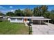 Inviting home featuring a bright orange door, carport, and well-maintained lawn at 1625 Avenue D Ne, Winter Haven, FL 33881