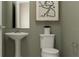 Cozy half bathroom with a pedestal sink, toilet, and modern wall art at 1917 Stake Out Way, Apopka, FL 32703