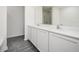 Bathroom features dual sinks, white cabinets, grey plank flooring, and a large mirror at 409 Ashbury Way, Poinciana, FL 34759