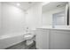A clean bathroom with a white tiled shower-tub, toilet, and vanity with white cabinets at 409 Ashbury Way, Poinciana, FL 34759