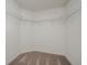 Walk-in closet featuring built-in shelving and neutral carpet at 409 Ashbury Way, Poinciana, FL 34759