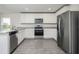 Modern kitchen with white cabinets, stainless steel appliances, granite countertops, and gray wood-look flooring at 409 Ashbury Way, Poinciana, FL 34759