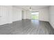 Open-concept living room with gray wood-look flooring, ceiling fan, and sliding glass doors to the backyard at 409 Ashbury Way, Poinciana, FL 34759
