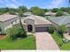 Aerial view of a single-story home with a well-maintained lawn, brick driveway, and an attached garage at 9362 Oglethorpe Dr, Groveland, FL 34736