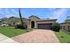Charming single-story home with a well-maintained lawn, brick driveway, and attached two-car garage at 9362 Oglethorpe Dr, Groveland, FL 34736