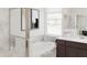 Bright bathroom with a soaking tub, glass shower, and sleek vanity with marble countertops at 5676 Vinyasa Rd, Clermont, FL 34714