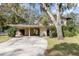 Beige two-story house featuring a covered carport, complemented by mature trees and manicured lawn at 819 22Nd Nw St, Winter Haven, FL 33881