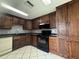 Traditional kitchen featuring dark wood cabinetry, a stainless steel refrigerator, and black appliances at 427 Donald St, Lakeland, FL 33813