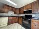 Traditional kitchen featuring dark wood cabinetry, a stainless steel refrigerator, and black appliances at 427 Donald St, Lakeland, FL 33813