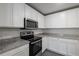 Well-lit kitchen with stainless steel microwave and oven, granite counters, and white cabinetry at 571 Bay Leaf Dr, Poinciana, FL 34759