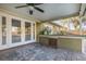 Covered outdoor patio featuring outdoor kitchen, ceiling fan, and access to the pool area at 6214 Elm E Sq, Lakeland, FL 33813