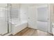Bright bathroom featuring a tiled shower, soaking tub with glass block window, and wood-look vinyl floors at 2726 Herons Landing Dr, Kissimmee, FL 34741