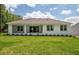 Back of house showing a covered patio, sliding glass doors, and lush green lawn at 2050 Nw 79Th Loop, Ocala, FL 34475