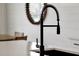 Close up on a modern black faucet and sink, with white countertop, mirror, and wooden chair in the background at 5789 Timber Meadow Way, St Cloud, FL 34771