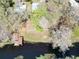 Aerial view of a property near a waterway, featuring a shed, dock, and a tree-filled landscape at 9461 Cr 657, Bushnell, FL 33513