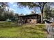 View of the home showing backyard with lush greenery and a screened porch, wooden deck and stairs at 9461 Cr 657, Bushnell, FL 33513
