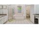 Bright bathroom featuring tiled floor, a garden tub with tiled surround, and a glass enclosed shower at 5261 Waterwood Dr, Bartow, FL 33830