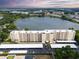 An aerial view shows a well-kept building on a lush green lawn with a lake view and covered parking at 700 Mirror Nw Ter # 505, Winter Haven, FL 33881