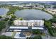 Elevated rear view of a building near a lake with mature trees, private docks, and community pool at 700 Mirror Nw Ter # 505, Winter Haven, FL 33881