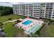 Aerial view of a community pool, shuffleboard court, and landscaping at condo complex at 700 Mirror Nw Ter # 505, Winter Haven, FL 33881