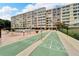 Multi-story building with manicured grounds, shuffleboard court, and outdoor lounge seating by the pool at 700 Mirror Nw Ter # 505, Winter Haven, FL 33881