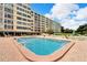 Sparkling pool with surrounding brick patio with poolside lounge seating and umbrellas at 700 Mirror Nw Ter # 505, Winter Haven, FL 33881