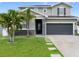 Beautiful two-story home with stone accents, gray siding, and a well-manicured lawn with palm trees at 1741 Hill Top Dr, Dundee, FL 33838