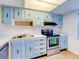 Sunlit kitchen with baby-blue cabinets, stainless steel sink and a black range at 333 Lake Howard Dr Nw # 314D, Winter Haven, FL 33880