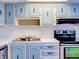 Bright kitchen with baby-blue cabinets, white countertops, a stainless steel sink and a black range at 333 Lake Howard Dr Nw # 314D, Winter Haven, FL 33880