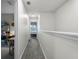 Upstairs hallway with gray carpet leading to bedrooms, featuring neutral paint and a view of a bedroom window at 3798 Plainview Dr, Orlando, FL 32824