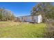 Exterior view of the home in an overgrown yard under a clear sky at 1140 Saddlewood Blvd, Lakeland, FL 33809