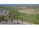 Expansive aerial view of a residential community bordered by dense woods and open fields at 6455 Sedgeford Dr, Lakeland, FL 33811