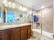 Well-lit bathroom features double sinks, tile flooring, framed mirror, and a shower with a glass door at 6455 Sedgeford Dr, Lakeland, FL 33811