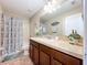 Well-lit bathroom featuring a vanity with a mirror, a shower with a patterned curtain, and tile flooring at 6455 Sedgeford Dr, Lakeland, FL 33811