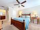 Cozy bedroom featuring an ornate headboard, ceiling fan, and natural light from the nearby bathroom at 6455 Sedgeford Dr, Lakeland, FL 33811