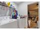 Laundry room with white washer and dryer, overhead shelving, and doorway to the garage at 114 Briarcliff Dr, Kissimmee, FL 34758